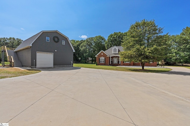 view of front of home with a garage, a front lawn, a gambrel roof, driveway, and an outbuilding