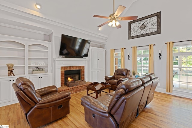 living room featuring light wood-type flooring, ceiling fan, vaulted ceiling, and a brick fireplace