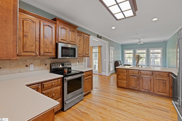 kitchen with light wood-type flooring, ornamental molding, stainless steel appliances, ceiling fan, and decorative backsplash