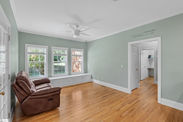 sitting room featuring baseboards, crown molding, light wood-style floors, and ceiling fan