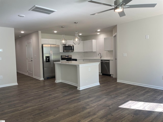 kitchen with a center island, appliances with stainless steel finishes, dark hardwood / wood-style floors, and ceiling fan