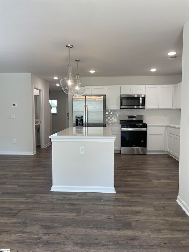 kitchen with white cabinets, appliances with stainless steel finishes, decorative light fixtures, and dark wood-type flooring