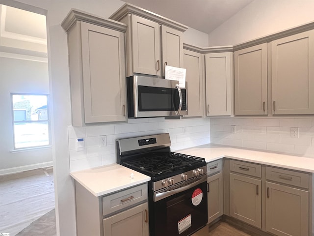 kitchen with appliances with stainless steel finishes, gray cabinets, backsplash, and hardwood / wood-style floors