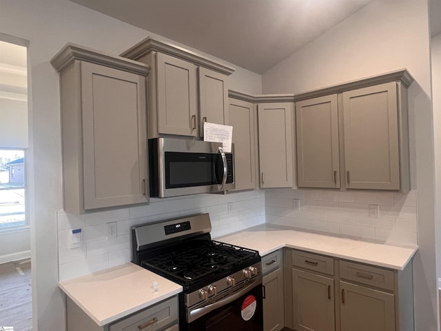 kitchen featuring lofted ceiling, appliances with stainless steel finishes, gray cabinets, and decorative backsplash