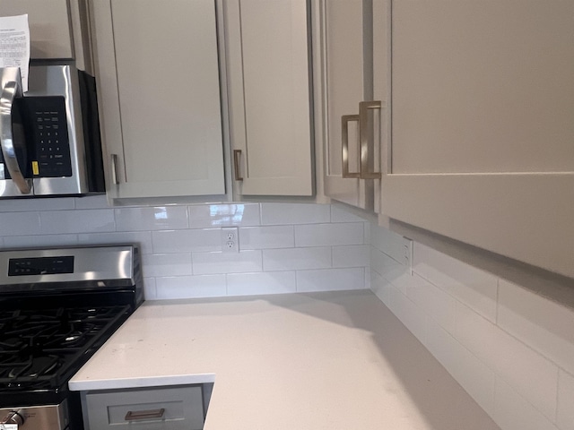 interior details with appliances with stainless steel finishes, backsplash, and gray cabinetry