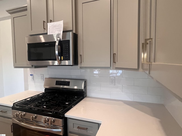 kitchen with stainless steel appliances, backsplash, and gray cabinets