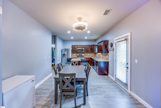 dining space with a healthy amount of sunlight, light hardwood / wood-style flooring, and sink