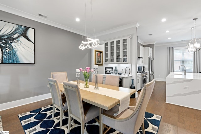 dining area with ornamental molding, dark hardwood / wood-style flooring, and sink