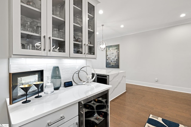 bar featuring wine cooler, light stone countertops, dark hardwood / wood-style flooring, hanging light fixtures, and ornamental molding