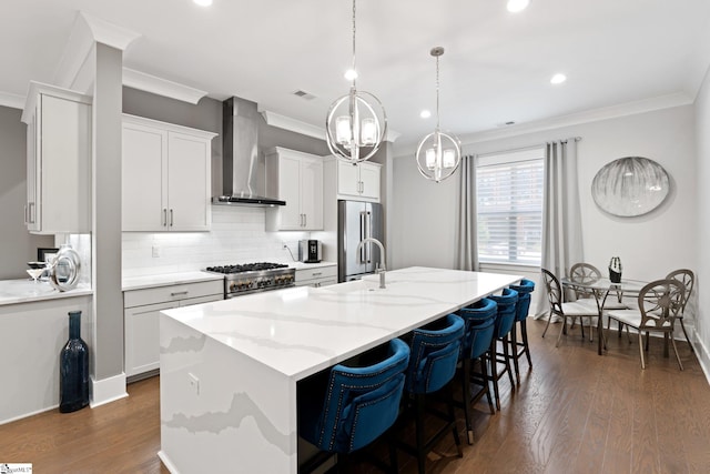 kitchen featuring pendant lighting, high quality appliances, dark hardwood / wood-style floors, a center island with sink, and wall chimney range hood