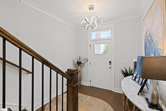 entryway with dark wood-type flooring, ornamental molding, and a chandelier