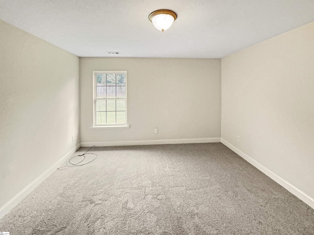 carpeted empty room featuring a textured ceiling