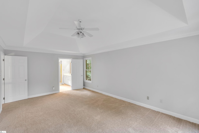 spare room featuring a tray ceiling, crown molding, ceiling fan, and light carpet