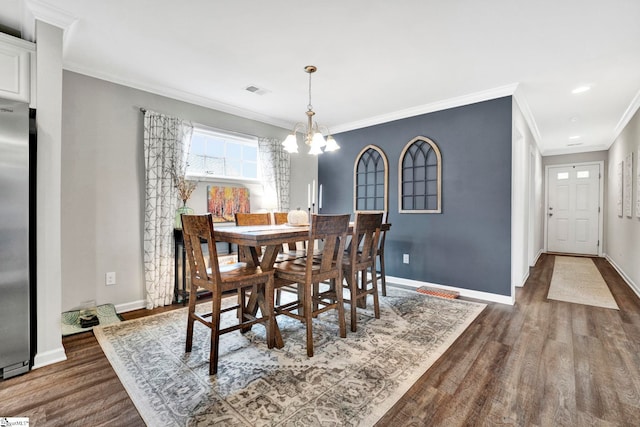 dining space with ornamental molding, dark wood-type flooring, and a notable chandelier