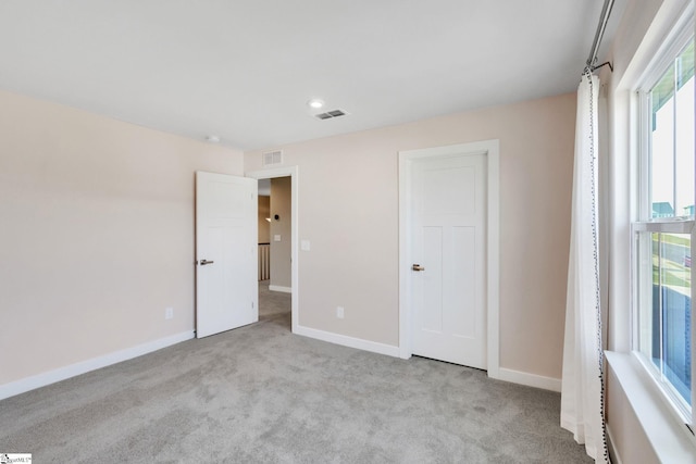 unfurnished bedroom featuring light colored carpet and multiple windows