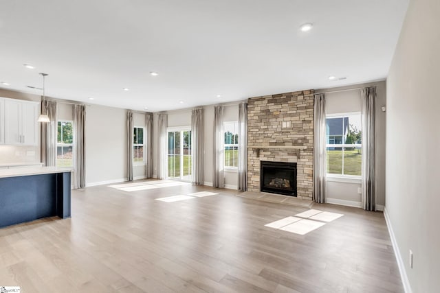 unfurnished living room with light hardwood / wood-style flooring and a stone fireplace