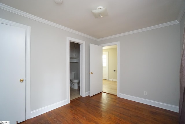 unfurnished bedroom with connected bathroom, dark wood-type flooring, and crown molding