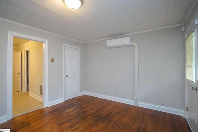 spare room featuring wood-type flooring, crown molding, and an AC wall unit