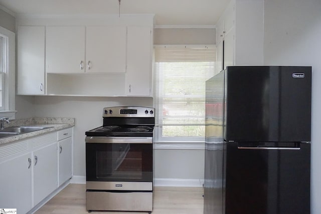 kitchen featuring stainless steel appliances, white cabinets, light wood-type flooring, and sink