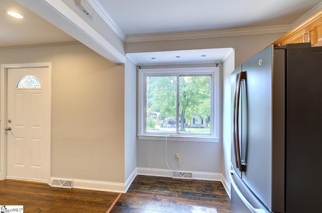 kitchen with a wealth of natural light, crown molding, dark wood-type flooring, and stainless steel refrigerator