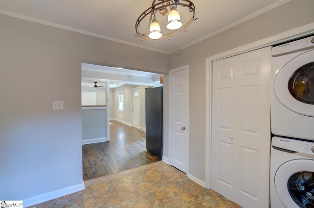 clothes washing area with ceiling fan with notable chandelier, dark wood-type flooring, crown molding, and stacked washer / drying machine