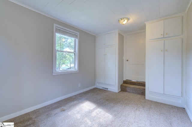 unfurnished bedroom featuring light carpet, a closet, and crown molding