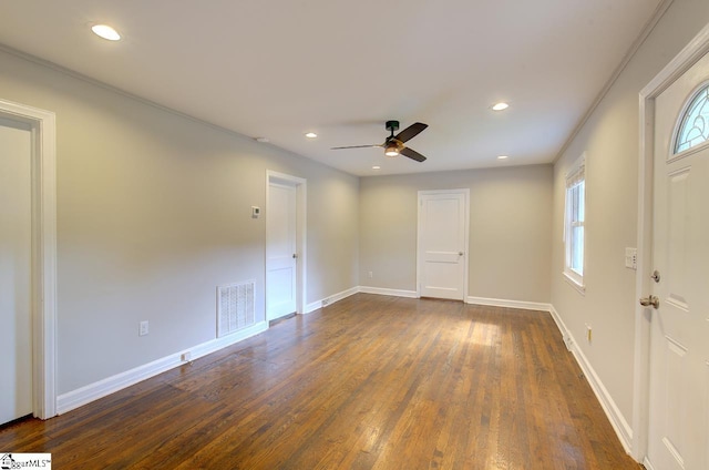 empty room featuring ornamental molding, a wealth of natural light, ceiling fan, and dark hardwood / wood-style floors