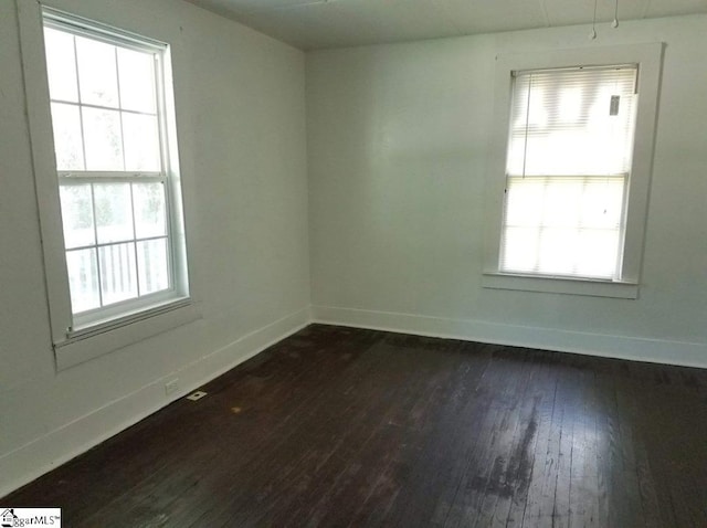 spare room with a wealth of natural light and dark hardwood / wood-style flooring