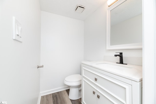 bathroom featuring hardwood / wood-style floors, a textured ceiling, vanity, and toilet