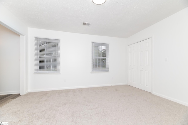 carpeted spare room featuring a textured ceiling