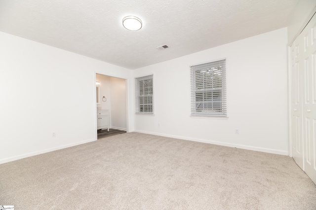 unfurnished bedroom with a textured ceiling, light carpet, and a closet