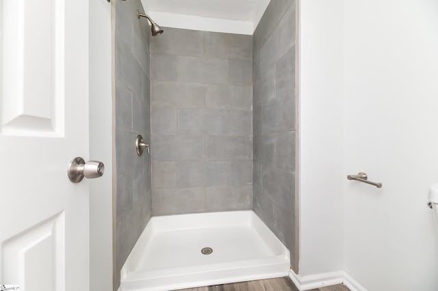 bathroom with a textured ceiling, hardwood / wood-style floors, and tiled shower