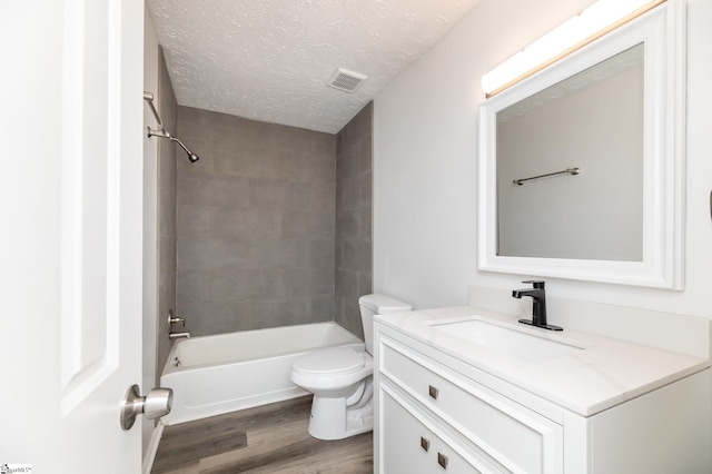 full bathroom featuring vanity, tiled shower / bath combo, a textured ceiling, hardwood / wood-style flooring, and toilet