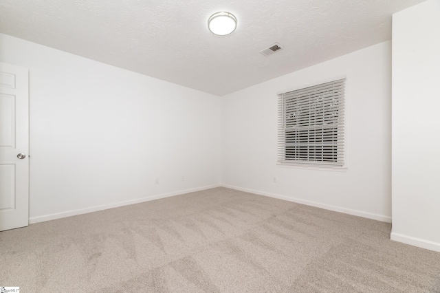 empty room with light colored carpet and a textured ceiling