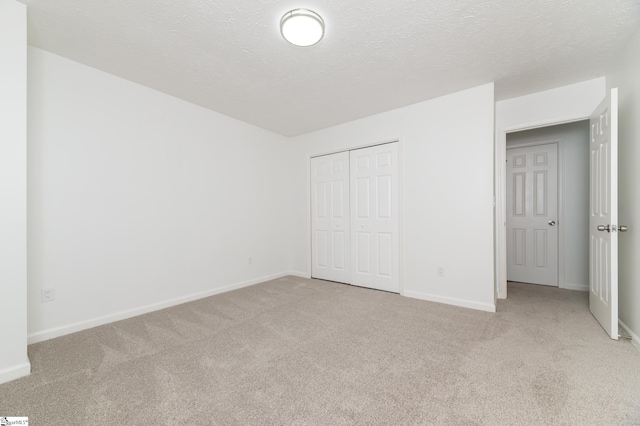 unfurnished bedroom featuring light carpet, a closet, and a textured ceiling