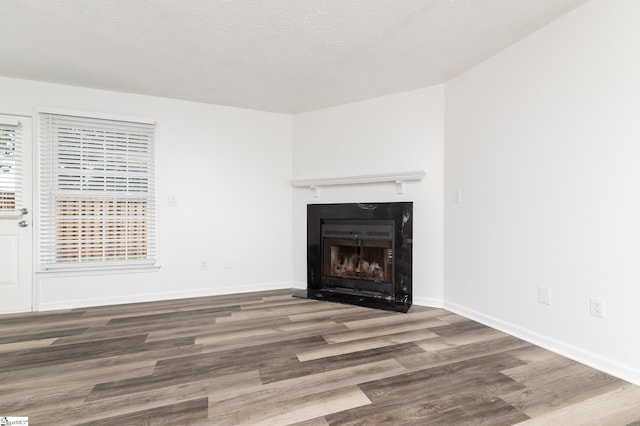 unfurnished living room with wood-type flooring and a textured ceiling