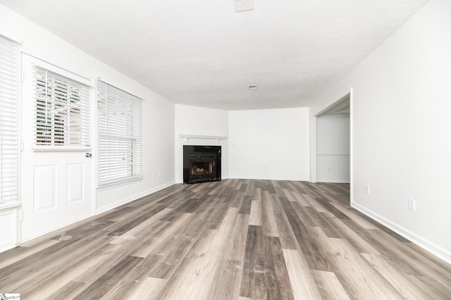 unfurnished living room with wood-type flooring and a textured ceiling