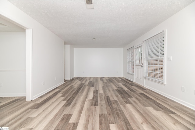 spare room featuring a textured ceiling and light hardwood / wood-style flooring