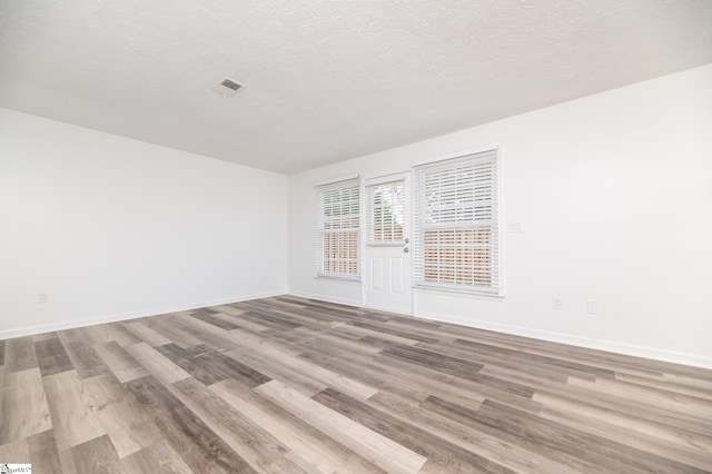 empty room featuring a textured ceiling and light hardwood / wood-style floors