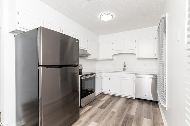 kitchen with light wood-type flooring, a textured ceiling, sink, white cabinetry, and appliances with stainless steel finishes