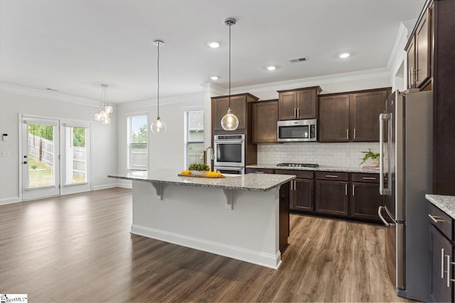 kitchen featuring appliances with stainless steel finishes, a kitchen island with sink, a breakfast bar area, and dark hardwood / wood-style flooring