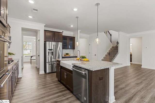 kitchen featuring a kitchen island with sink, sink, stainless steel appliances, dark brown cabinetry, and dark hardwood / wood-style flooring