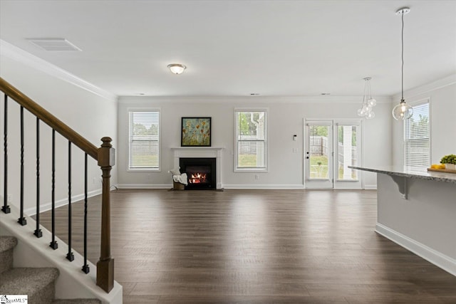 unfurnished living room with dark hardwood / wood-style floors, ornamental molding, a chandelier, and a wealth of natural light