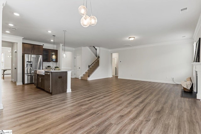 kitchen featuring appliances with stainless steel finishes, hanging light fixtures, dark brown cabinets, a kitchen island with sink, and dark hardwood / wood-style floors