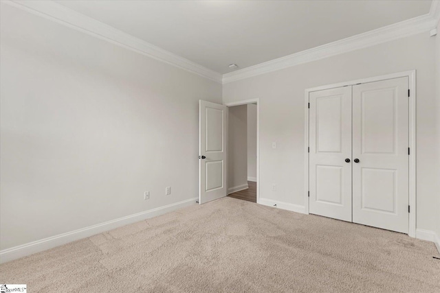 unfurnished bedroom with a closet, light colored carpet, and crown molding