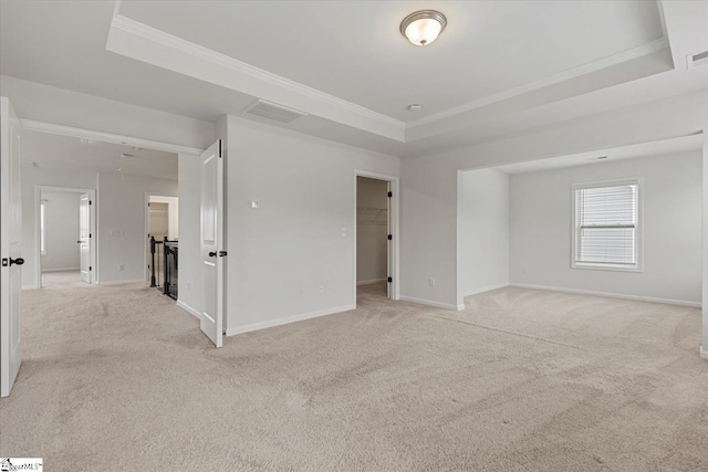 carpeted empty room with ornamental molding and a tray ceiling