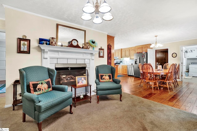 living area featuring a textured ceiling, crown molding, a tile fireplace, and an inviting chandelier