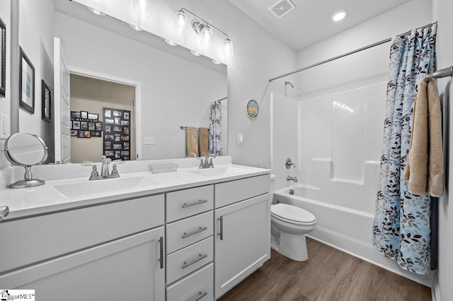 full bathroom featuring wood-type flooring, shower / tub combo with curtain, vanity, and toilet