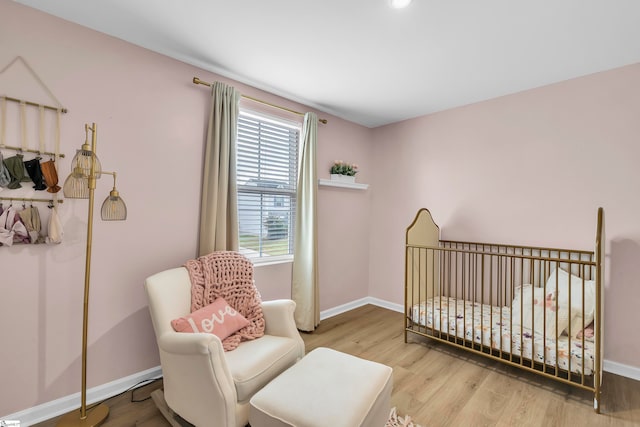 bedroom with wood-type flooring and a nursery area