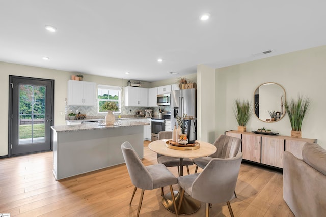 dining area with light wood-type flooring and plenty of natural light